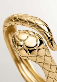 Pulsera de serpiente de oro con escamas texturizadas y acentos suaves. Presenta un diseño en espiral, destacando los intrincados detalles en la cabeza de la serpiente.