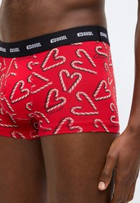 Piros boxeralsó cukorpálcák és szívek mintájával. Fekete elasztikus derékrész "Diesel" logóval. Puha, rugalmas anyagból.