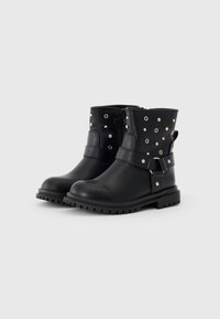 Botas de tobillo negras hechas de cuero sintético, con tachuelas decorativas, correa ajustable, cremallera lateral y suela resistente para tracción.
