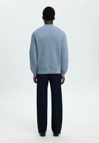 Lichtblauwe geribbelde trui met lange mouwen, ronde hals en een relaxed fit, gecombineerd met donkere marineblauwe wijde broek.