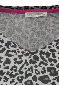 Top grigio con stampa leopardata nera, design a V, accentuato da cuciture rosa e un'etichetta con la scritta "KEY LARGO", taglia XS. Texture liscia.