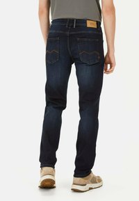Donkerblauwe spijkerbroek met een slim fit, voorzien van gestikte achterzakken, een leren label op de tailleband en subtiele vervaging.