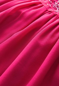 Fuchsia jurkstof met een gladde textuur, voorzien van geplooide details en versierd met kleine, decoratieve kralen nabij de halslijn.