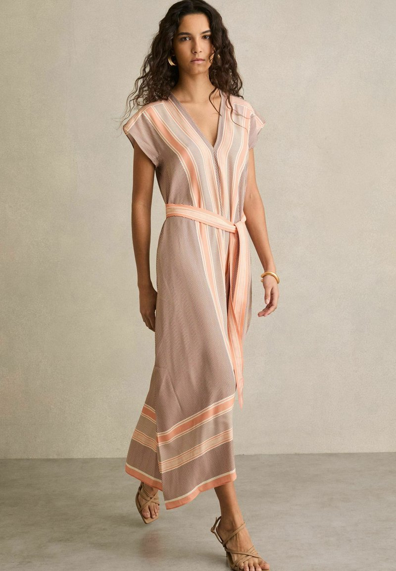 Maxime dress in ruskea ja persikka, jossa on sahalaitakuosi, lyhyet hihat ja sidottava vyö; sisältää V-päinen kaula-aukko ja raidalliset yksityiskohdat helmassa.