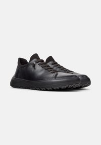Sneaker in pelle nera con finitura testurizzata, punta rotonda e chiusura con lacci. Suola in gomma nera con motivi di trazione.
