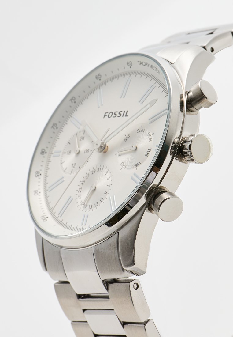 Montre en acier inoxydable argenté avec un cadran blanc, dotée d'un tachymètre, de sous-cadrans chronographe et de trois poussoirs. Index luminescents.