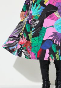 Bunt gemustertes knielanges Kleid mit einem auffälligen Blumen- und Blättermuster auf schwarzem Hintergrund, verziert mit lebhaften Akzenten in Pink, Grün und Blau.