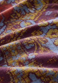 Material textil cu un model texturat cu bumbăceală în nuanțe de vișiniu, albastru și galben, cu forme abstracte îndrăznețe și culori contrastante.
