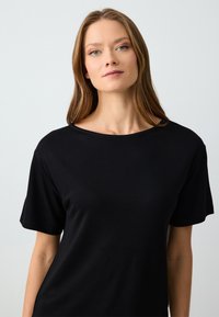 Zwarte T-shirt met korte mouwen en een ronde hals, gemaakt van een gladde stof, met een comfortabele pasvorm en een minimalistisch ontwerp.