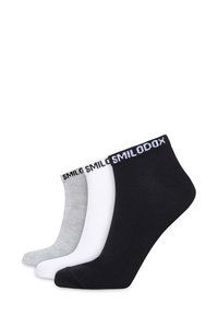 Tres pares de calcetines de tobillo en negro, blanco y gris. Cada uno presenta una textura suave y cómoda con una banda acanalada y un logo en la parte superior.