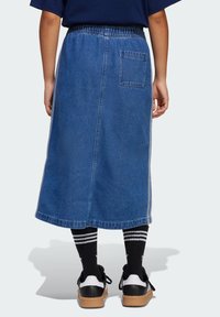 Denim midi skjørt med en avslappet passform, elastisk midjebånd og en enkelt baklomme. Har blått stoff og kontrasterende sømmer på siden.