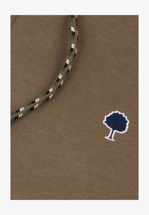 Brauner Stoff mit einem geflochtenen Zugband, das weiße, schwarze und türkisfarbene Akzente aufweist, sowie einem kleinen gestickten Logo eines dunkelblauen Baumes.