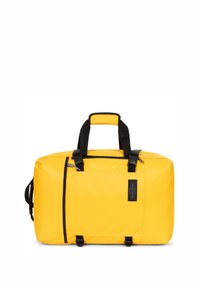 Gul duffelväska i hållbart material, med svarta metalldetaljer, två handtag, justerbar rem och en framficka med varumärke.