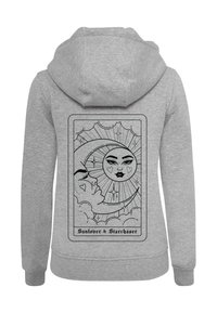 Sudadera gris con un diseño gráfico negro en la parte posterior, que representa un sol, una luna y rostros dentro de un marco con texto debajo.