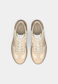 Baskets crème et pêche au design rétro, avec un haut texturé, des lacets et une semelle en caoutchouc beige. Étiquette visible sur la languette.