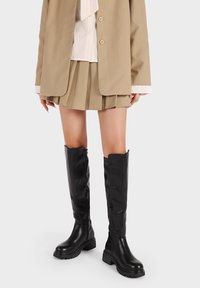 Stivali neri al ginocchio con una finitura liscia e lucida, dotati di zip laterali e suole in gomma spesse per una maggiore trazione.