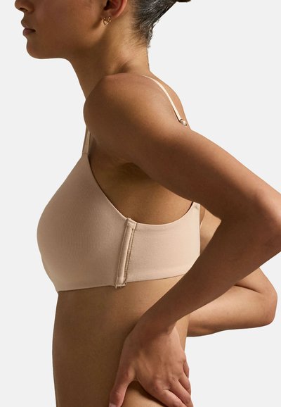 Reggiseno beige a coste con spalline regolabili, texture liscia e chiusura a gancio sul retro. Design semplice e colore neutro.