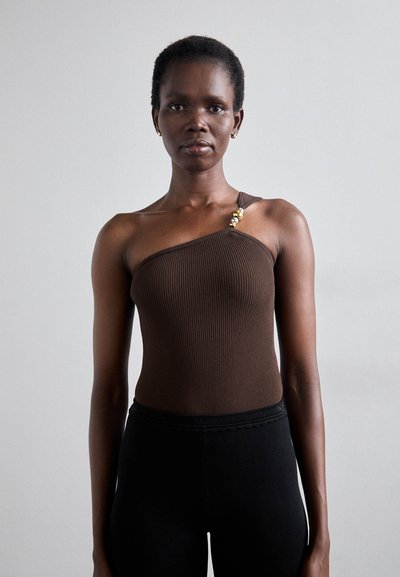 Brun ribbet bodysuit med en-enskulder design, prydet med en guldsmykke accent på stropen, parret med sorte tætsiddende bukser.