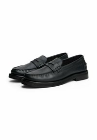 Mocasines de cuero negro con puntera cosida, banda decorativa en la parte superior y suela de goma plana. Textura suave y diseño aerodinámico.