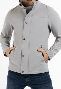 Veste softshell grise avec col montant, boutons-pression et poches latérales. Présente une texture lisse et une coupe ajustée.