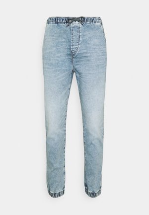 Pantalon de jogging en denim délavé bleu clair avec taille élastique et poignets aux chevilles, ainsi qu'un cordon noir à la taille.