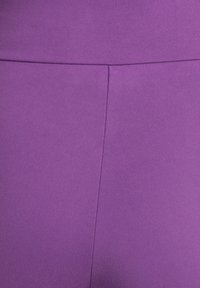Tissu violet ajusté avec une texture lisse. Le design présente une couture verticale au centre pour un détail supplémentaire.