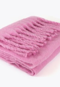Lyserød uldtæppe med en blød tekstur, der har frynser langs den ene kant. Tæppet er pænt foldet.