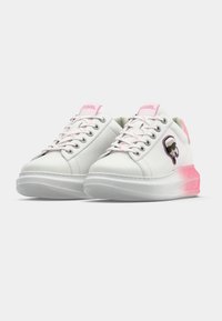 Λευκά αθλητικά παπούτσια με ροζ κορδόνια και λεπτο μέρειες, διαθέτουν λείο δερμάτινο επάνω μέρος, στρογγυλή μύτη και διαφανές λαστιχένιο πάτο. Φαίνεται το χαρακτηριστικό λογότυπο.