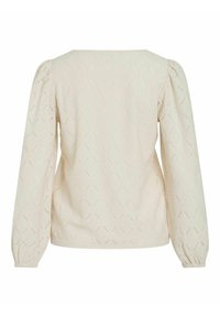 Kremowa bluzka o teksturze z długimi puffowanymi rękawami, z geometrycznym wzorem w romby i kwadratowym dekoltem. Materiał jest lekki i lekko przezroczysty.