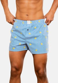 Blaue und weiße gestreifte Shorts mit Mustern von gelben Gummienten. Hergestellt aus leichtem Stoff, mit einem elastischen Taillenbund und Taschendetails.