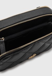 Czarna torba z teksturowanej skóry z zamkiem błyskawicznym, złotymi okuciami, pikowanym wzorem oraz wewnętrzną kieszenią na zamek.