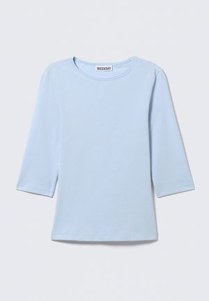 Ανοιχτό μπλε μπλούζα με μακριά μανίκια και στρογγυλή λαιμόκοψη, με απλό σχέδιο και ετικέτα "WEEKDAY" στο πίσω μέρος του γιακά.