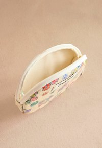 Cosmetica-etui met bloemenpatroon in crèmekleurige stof, met een ritsluiting, zachte textuur en een compact ovale vorm.