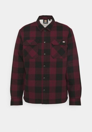 Chemise en flanelle à carreaux rouges et noirs, avec un devant à boutons, deux poches poitrine et une doublure intérieure douce.