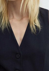 Gilet noir à fines rayures avec un col en V, comportant deux boutons à l'avant et un tissu lisse et texturé.