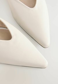 Valkoiset nahka ballet-loafers, joissa on terävä kärki. Suunnistus on sileä ja yksinkertaisilla yksityiskohdilla, ja sivuissa on avoin leikkaus.