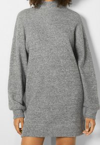 Abito grigio a maglia con scollo alto, spalle cadenti e maniche lunghe. Presenta un tessuto testurizzato e un orlo sopra il ginocchio.