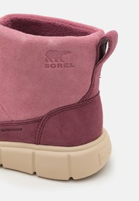 Vannavstøtende rosa semsket ankelstøvlett med en beige gummisåle. Har hevet merkevare og sømdetaljer på hælen.