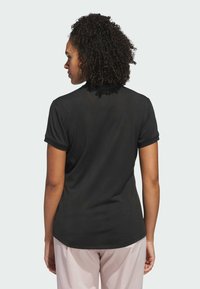 Maglietta nera a maniche corte realizzata in tessuto testurizzato, con colletto rotondo e vestibilità rilassata. Presenta risvolti sui polsini e un design semplice sul retro.