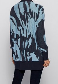 Stickad tröja med ett blått och marinblått abstrakt mönster, långa ärmar, rundad halsringning och en något oversized passform med ribbat nederkant.