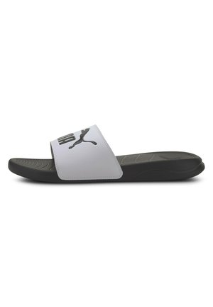 Chancla blanca con un logo negro, con una correa ancha y una suela texturizada negra. Diseño de punta redondeada con una textura de superficie suave.