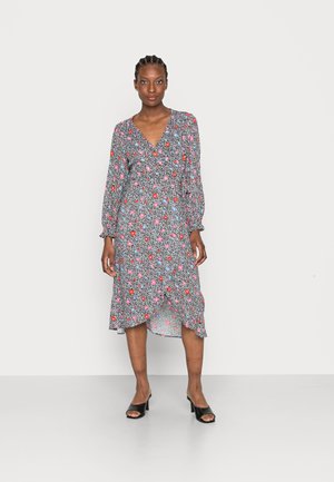 Vestido midi floral com fundo preto, apresentando flores rosas e azuis, mangas longas, decote em V e um裾 plissado. Sapatos de salto aberto pretos.