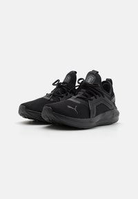 Schwarze Sportschuhe aus Mesh und Gummi, mit Schnürsenkeln, einem gepolsterten Schaft und einer strukturierten Sohle mit dezenten Branding-Elementen.