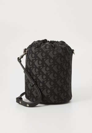 Musträkkide lõikega must nööriga ämbritask, mis on valmistatud tekstureeritud kangast; sisaldab peent mustrit ja reguleeritavat nahkrihma koos metallklambrite ja detailidega.