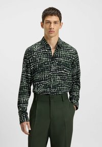 Camicia a maniche lunghe nera con un motivo a griglia bianco testurizzato; tessuto leggero; abbinata a pantaloni verde scuro; design con bottoni.