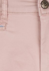 Lichtroze denimstof met een gladde textuur en subtiele diagonale weving. Bevat een metalen knoop en gestikte details nabij de tailleband.