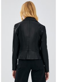 Black leather jacket with a fitted design, featuring a notched collar, seam detailing, and zippers at the cuffs. Back view shown.