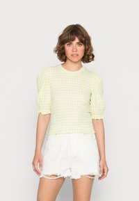 Top de puff-sleeve em gingham amarelo claro com gola redonda e tecido texturizado, combinado com calções brancos desfiados.