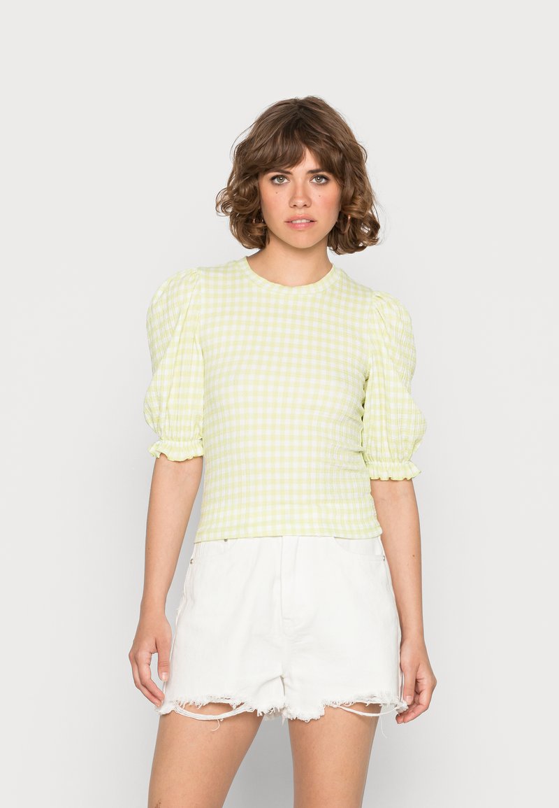 Top de puff-sleeve em gingham amarelo claro com gola redonda e tecido texturizado, combinado com calções brancos desfiados.