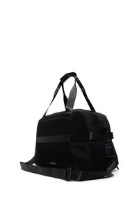 Schwarze Duffle-Tasche aus Netz- und festem Stoff, rechteckige Form, doppelte Griffe, verstellbarer Schulterriemen und angehängtes Etikett.